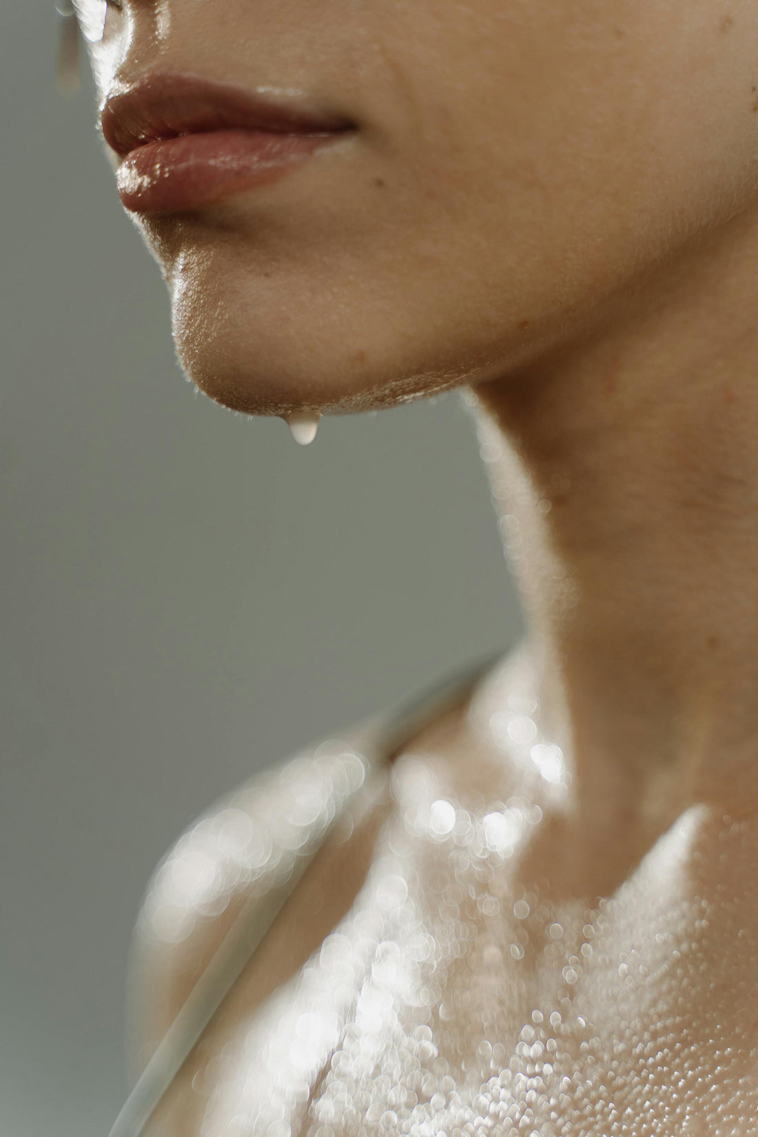 Close-up of a woman with water droplets on her neck, representing refreshment and hydration.