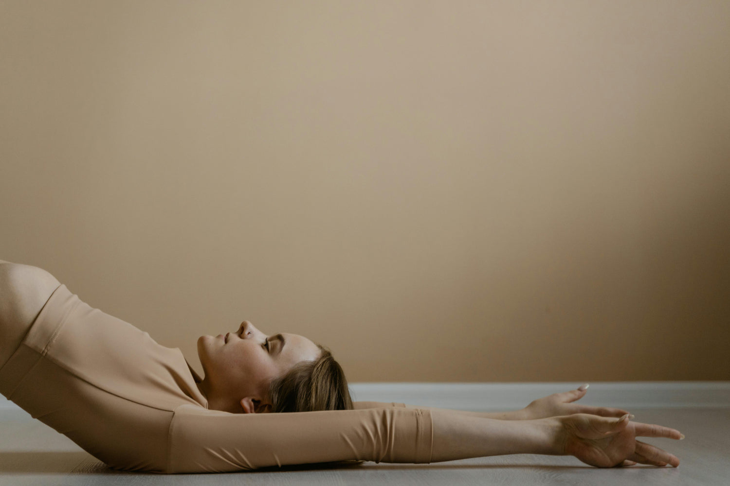 A woman lying on the floor during a yoga session, embodying tranquility in the Fall Reset collection.