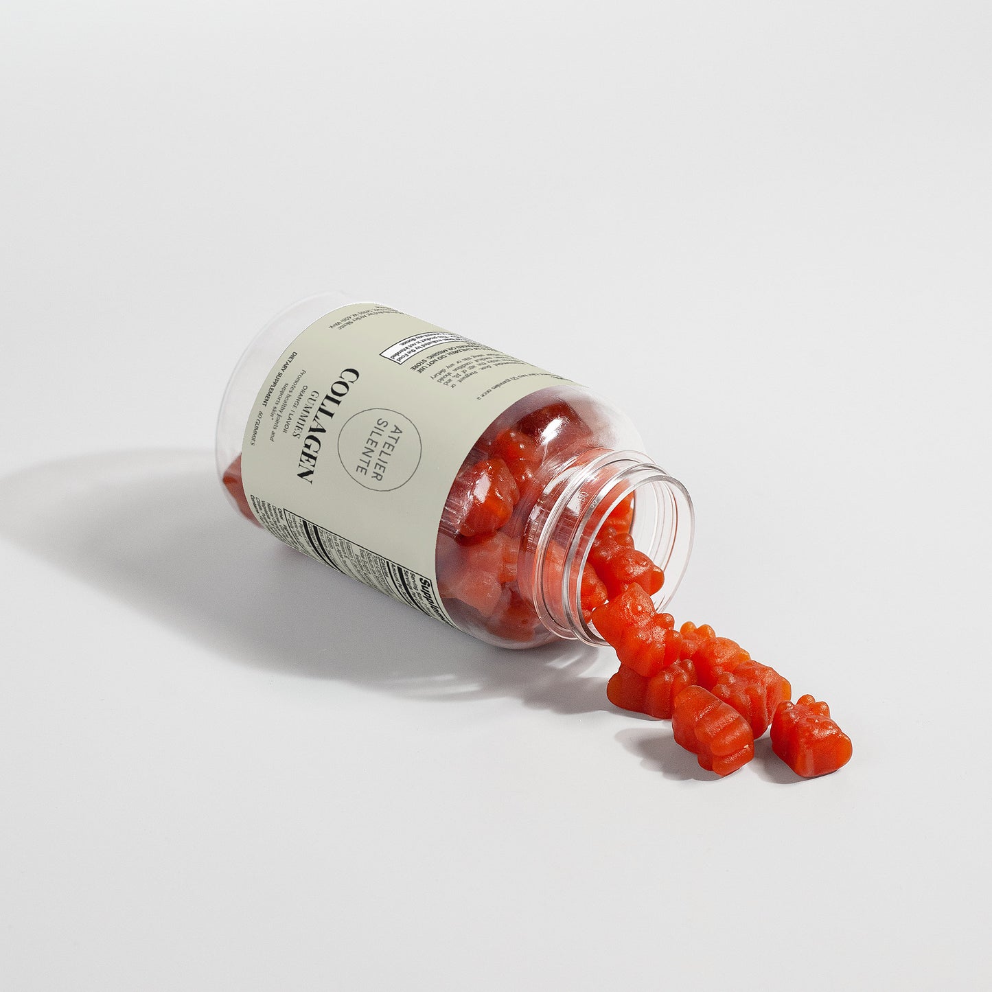 Collagen Gummies with Biotin spilling from an open bottle on a white background.
